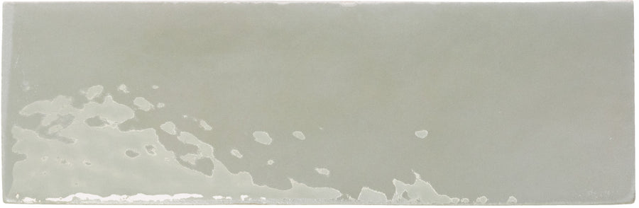 The Rebels 2" x 6" Matte Subway Tile features a rectangular, light gray design with subtle shade variations and a slightly wavy texture along the bottom left edge—ideal for accent walls.