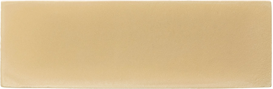 A rectangular Rebels 2" x 6" Matte Subway Tile in mustard matte color, featuring a smooth, unmarked surface that resembles sandpaper but with no visible patterns.
