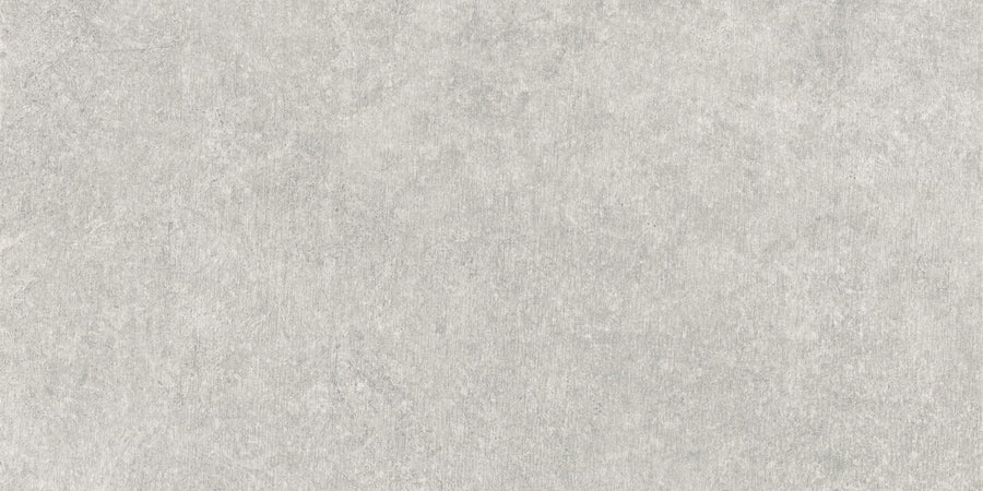 Revolve 12x24 Rectified Porcelain Tile features a light gray, stone-like surface with subtle shading variations and smooth, faint irregular patterns, giving it the contemporary look of concrete or natural stone.