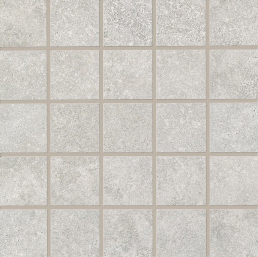 A grid of 25 light gray, stone-like Revolve 2x2 Mosaic Porcelain Tiles is arranged in five rows and five columns, each separated by thin beige grout lines for a decorative wall finish.