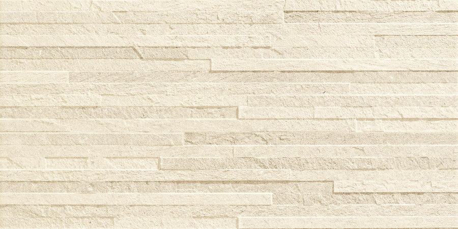 The Revolve 12x24 Muretto Porcelain Tile features textured beige tones and uneven rectangular formats, offering a layered, modern look. Its rough, natural finish with subtle color and texture variations adds visual interest to any space.