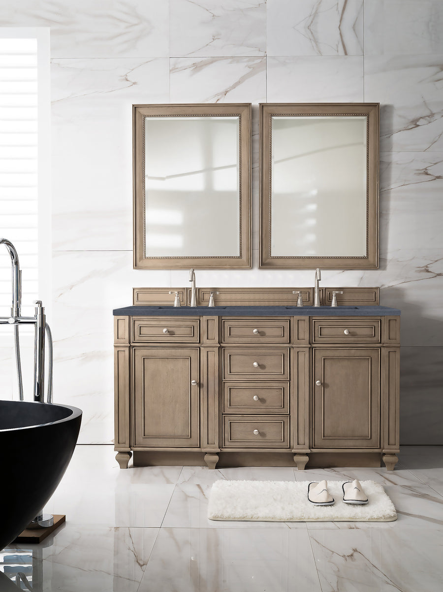 A modern bathroom features a Bristol 60" Double Bowl Vanity, two mirrors, silver faucets, a white rug with sandals, marble walls, and a partial view of a black bathtub on the left.