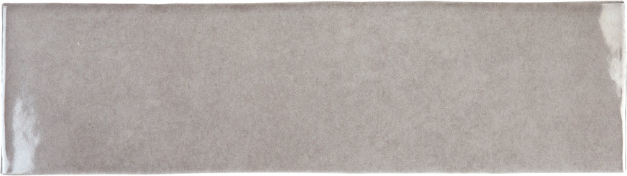 The Radiance 3" x 10" Glossy Subway Tile in Pumice features a light gray, textured finish and slightly uneven edges—ideal for accent walls or kitchen backsplashes—shown from above on a white background.