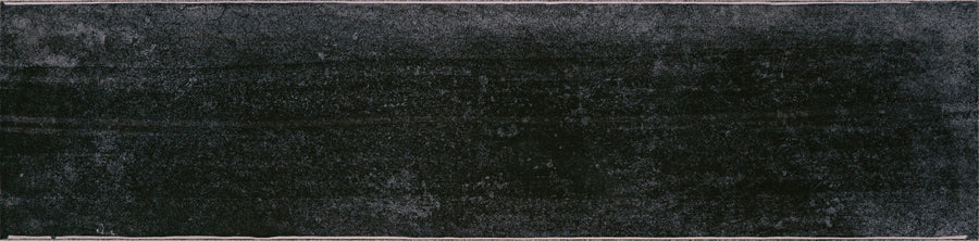 The Muse 4" x 16" Glossy Subway Tile in Cinder features a textured black surface with faint white outlines, evoking the look of a slightly worn chalkboard and adding modern style to any wall.
