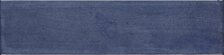 The Muse 4" x 16" Glossy Subway Tile in Denim features a textured, rectangular design with deep blue hues and visible brush strokes—ideal for adding artistic flair to contemporary wall tile projects.
