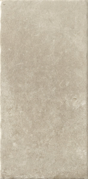 The VersaTILE 8x16 Glazed Porcelain Tile in Belgian Light features a rectangular shape, slightly textured matte finish, subtle color variations for a stone-like look, and gently uneven edges for added rustic charm.