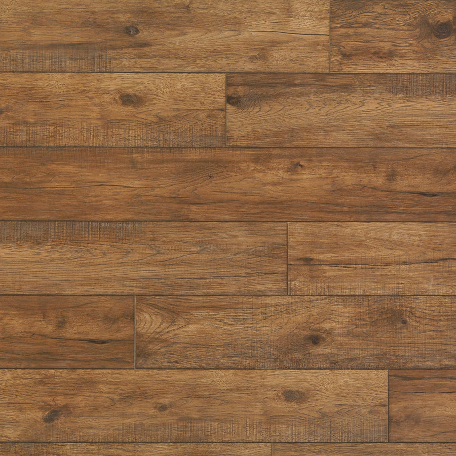A close-up of Hillside Hickory 7 9/16" Waterproof Laminate in Ember shows rich brown planks with natural wood grain and subtle color variations, arranged in a staggered horizontal layout.