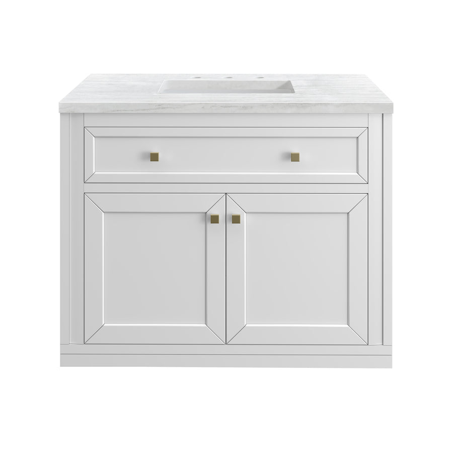 White bathroom vanity with a rectangular marble countertop, a built-in sink, one wide drawer with square gold handles, and two cabinet doors below with matching gold handles, all set against a plain white background.