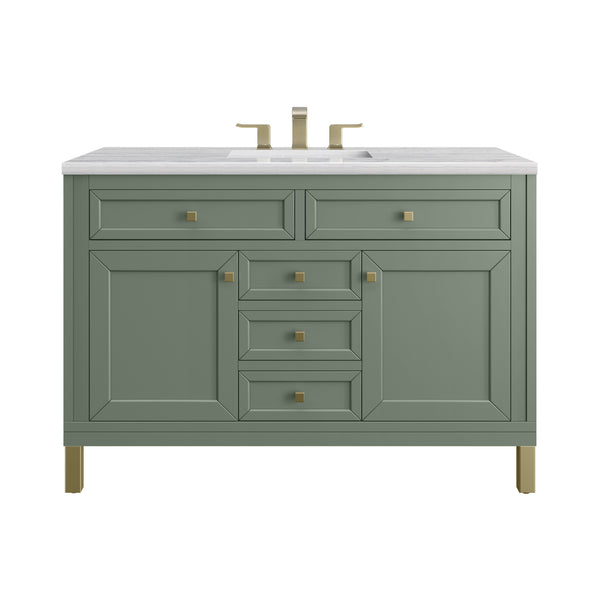 A sage green bathroom vanity with gold hardware, four central drawers, two side cabinets, and a white countertop featuring a built-in sink and gold faucet.