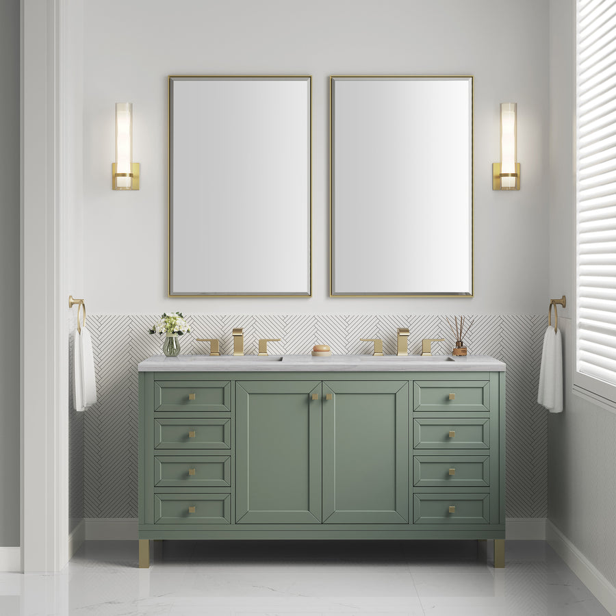 A modern bathroom features the Chicago 60" Double Bowl Vanity in sage green with gold fixtures, two large rectangular mirrors, wall sconces, white walls, a window with blinds, and neatly arranged decorative items and towels for added elegance.