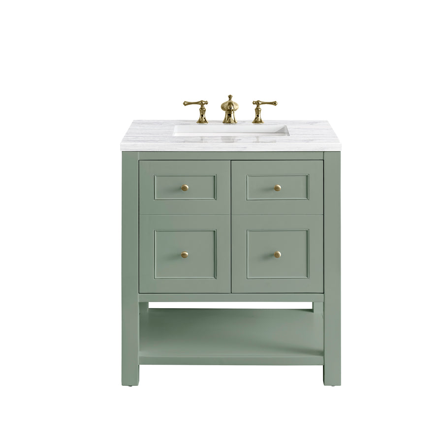 A light green bathroom vanity with a white marble countertop, brass faucet, four square drawer fronts with brass knobs, and an open lower shelf.