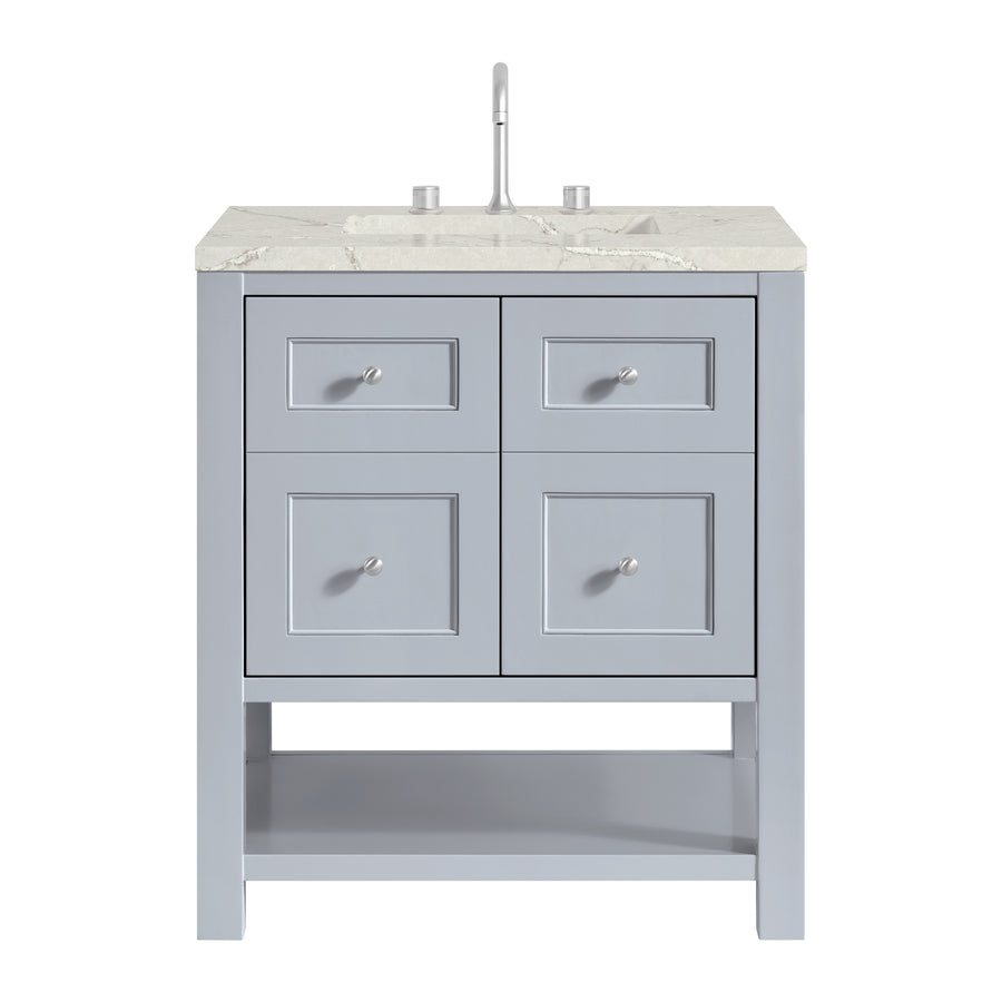 A light gray bathroom vanity with a marble countertop, a single faucet, four drawers with round silver knobs, and an open lower shelf.