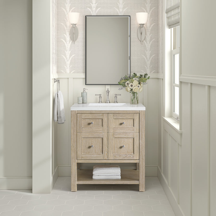 The Breckenridge 30" Vanity with a white countertop, paired with a rectangular mirror, wall sconces, and white flowers, enhances this bright neutral bathroom—ideal for transitional style.