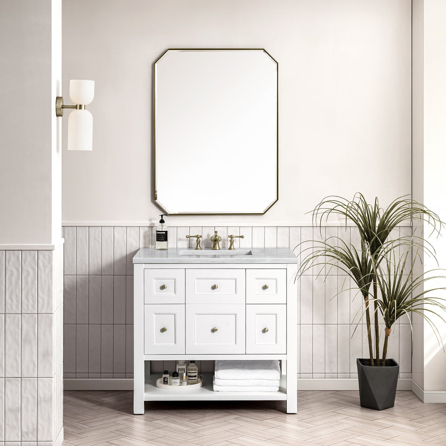 A modern bathroom showcases the Breckenridge 36" Vanity, brass fixtures, a large octagonal mirror, folded towels, a potted plant, and a two-light wall sconce on white tiled walls for a transitional look.