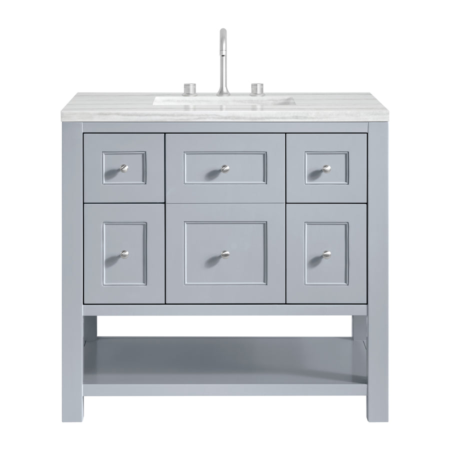 Light gray bathroom vanity with six drawers, a white marble countertop, an under-mount sink, a silver faucet, and an open shelf at the bottom. The vanity has small round silver knobs on each drawer.