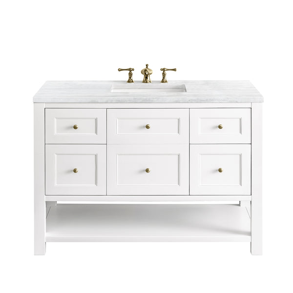 White bathroom vanity with a marble countertop, brass sink fixtures, and six drawers. The vanity has a lower open shelf and a rectangular undermount sink in the center.