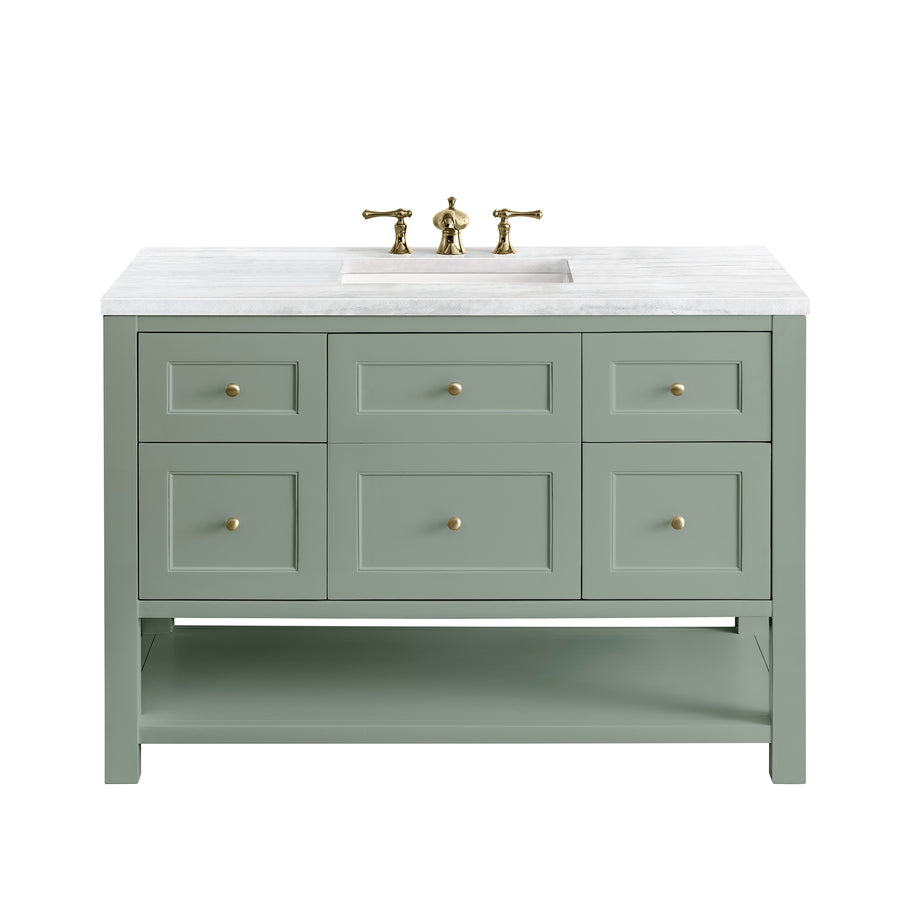 A light green bathroom vanity with six drawers, brass knobs, a white marble countertop, an under-mount sink, and a brass faucet. The vanity also has an open shelf at the bottom for extra storage.
