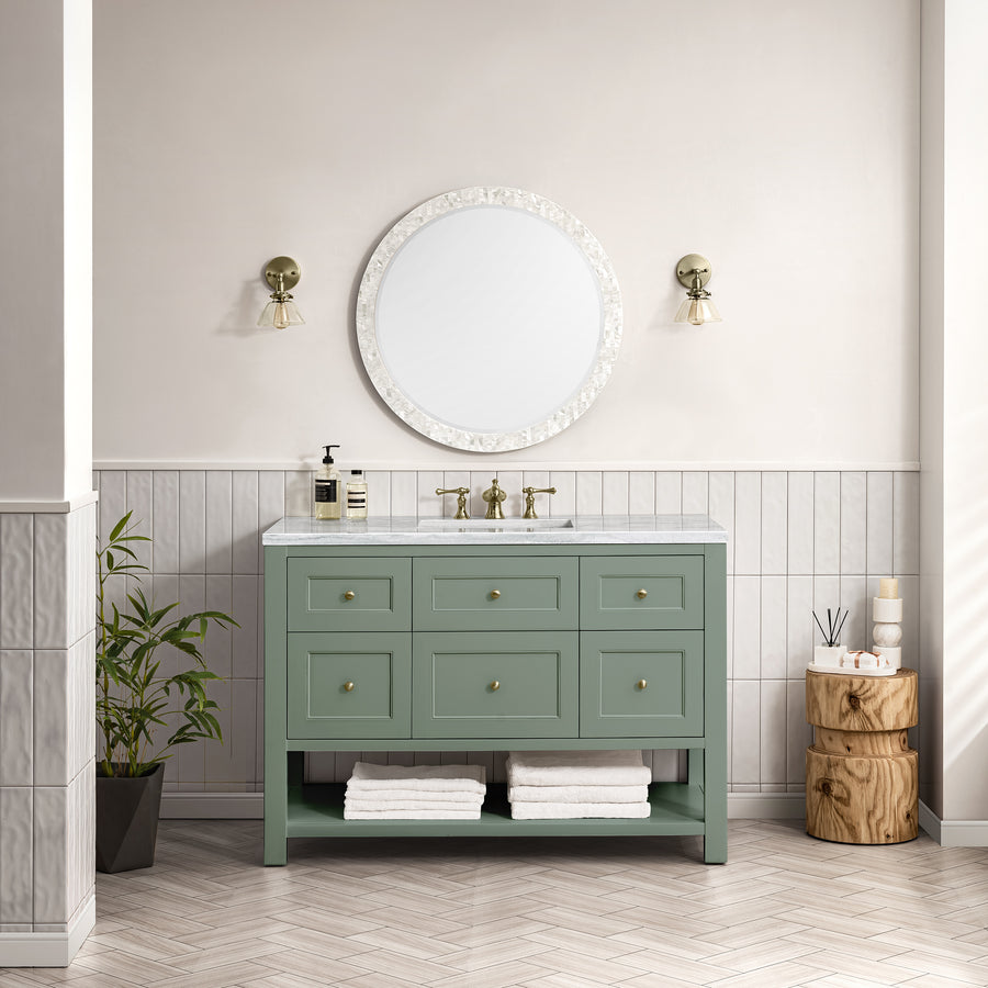 Elegant bathroom with the Breckenridge 48" Vanity, marble countertop, round mirror, wall sconces, stacked wood stools, potted plant, and neatly folded white towels—showcasing transitional design and luxury craftsmanship.