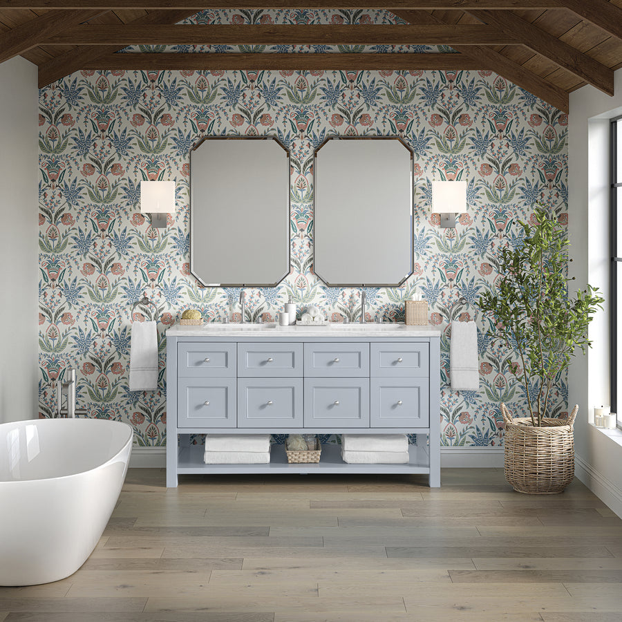 A stylish bathroom with floral wallpaper, the Breckenridge 60" Double Bowl Vanity in blue, two mirrors, wall sconces, a freestanding tub, a woven basket, wood ceiling beams, and natural light streaming through a large window.