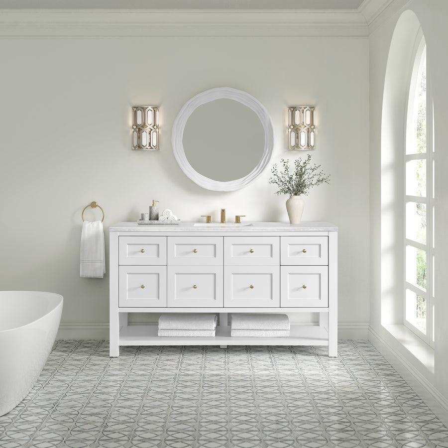 A bright, modern bathroom features a Breckenridge 60" Vanity with gold fixtures, a round mirror, wall sconces, towel ring and white towel, decorative vase, and patterned tile floor in a transitional style by a large arched window.