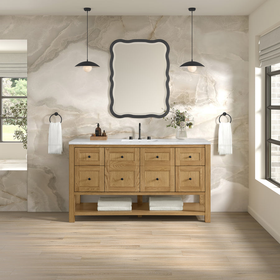 A modern bathroom featuring the Breckenridge 60" Vanity in light wood, a marble backsplash, scalloped rectangular mirror, pendant lights, and white towels. Sunlight from the right window highlights its transitional design.