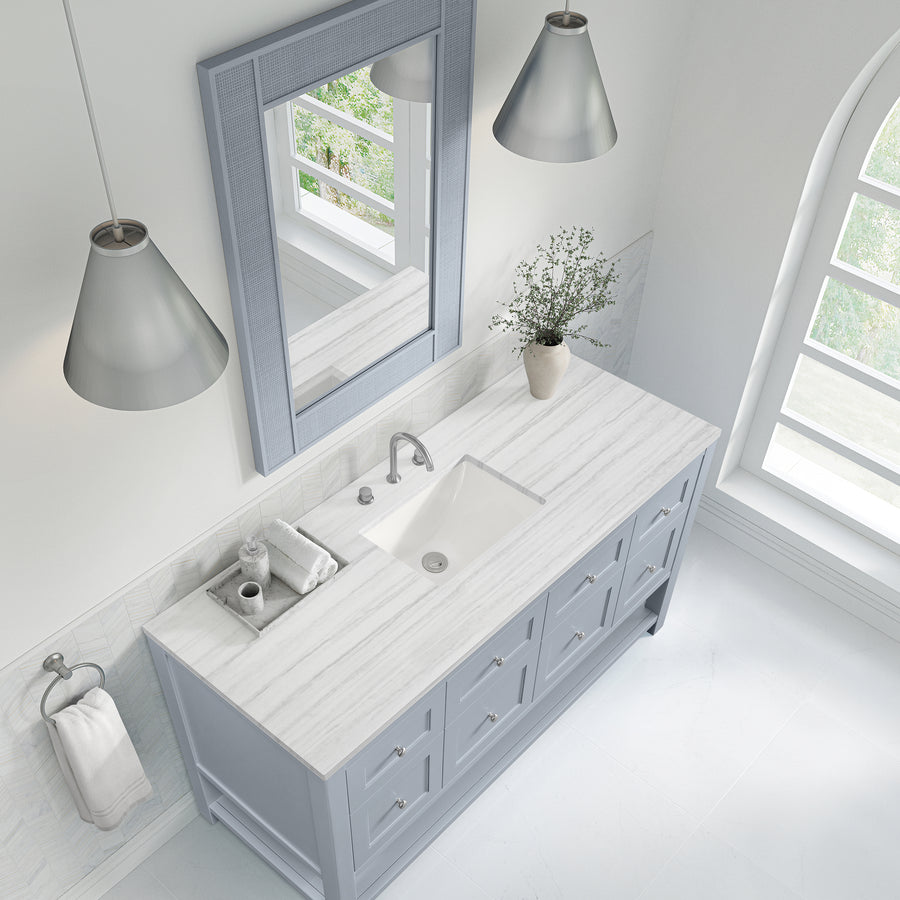 A bright, modern bathroom with a marble countertop, gray vanity, rectangular sink, silver faucet, large mirror, two pendant lights, a hand towel, and a vase with greenery next to an arched window.