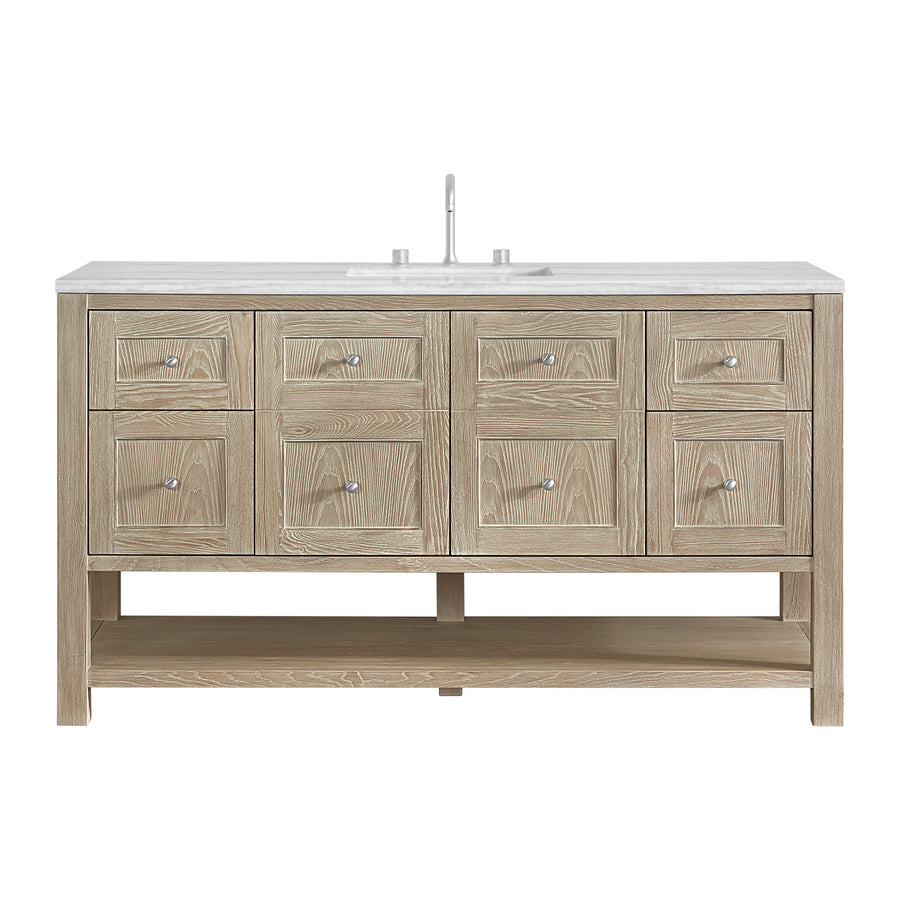 A wooden bathroom vanity with six drawers, two cabinet doors, a white countertop, an undermount sink, and a modern faucet. The vanity has an open lower shelf and a light natural wood finish.