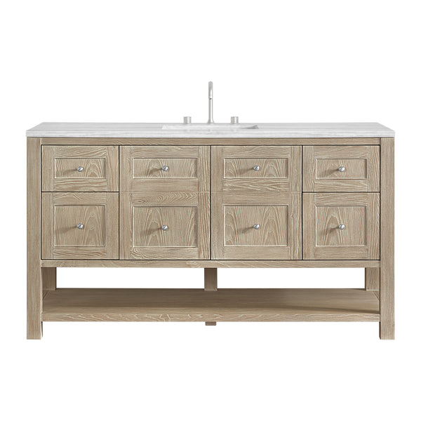 A wooden bathroom vanity with six drawers, two cabinet doors, a white countertop, an undermount sink, and a modern faucet. The vanity has an open lower shelf and a light natural wood finish.