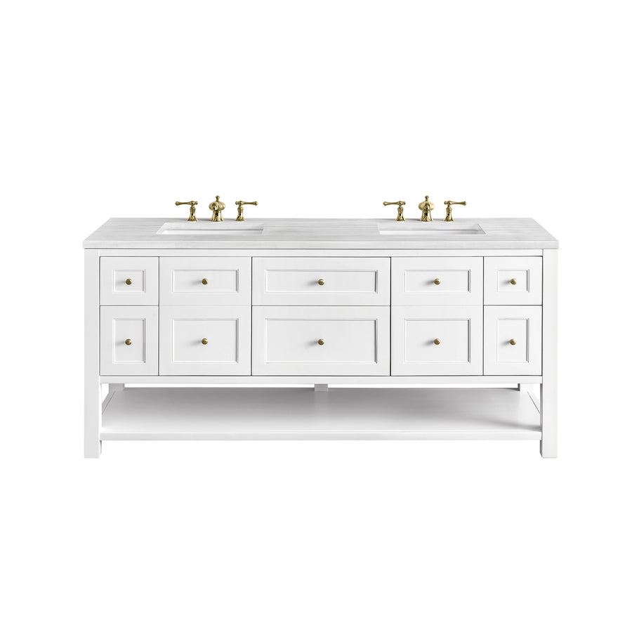 A white double sink bathroom vanity with six drawers, four cabinet doors, two sinks, gold faucets, and gold drawer knobs. There is an open shelf at the bottom. The vanity is on a white background.