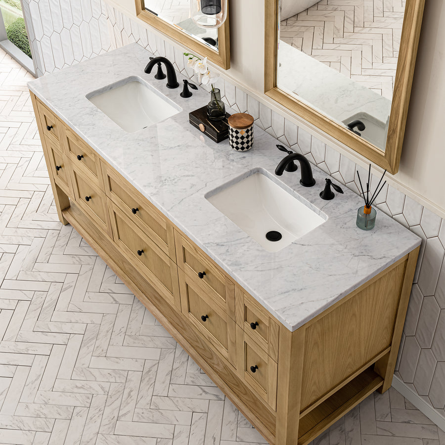 A bathroom vanity with a white marble countertop, two rectangular sinks, black faucets, and wooden cabinets, placed on a white herringbone tile floor beneath two large mirrors.