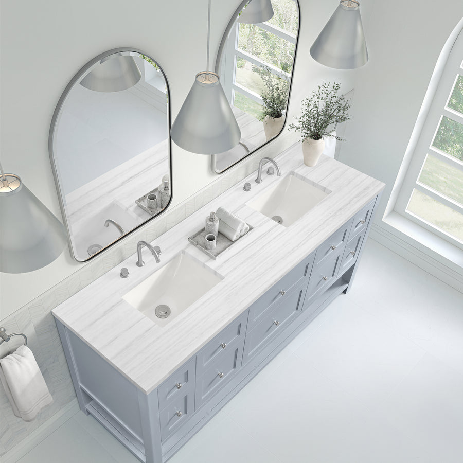 Bright, modern bathroom with a double-sink vanity, marble countertop, large mirrors, sleek faucets, pendant lights, drawers, a vase with greenery, and a nearby arched window letting in natural light.