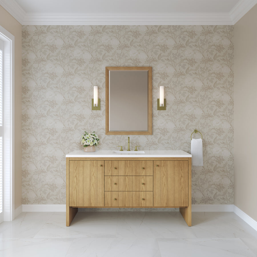 A modern luxury bathroom featuring a stylish Hudson 60″ Vanity in Light Natural Oak, floral wallpaper, a rectangular mirror, two elegant wall sconces, a towel ring, and a vase of white flowers gracing the countertop.