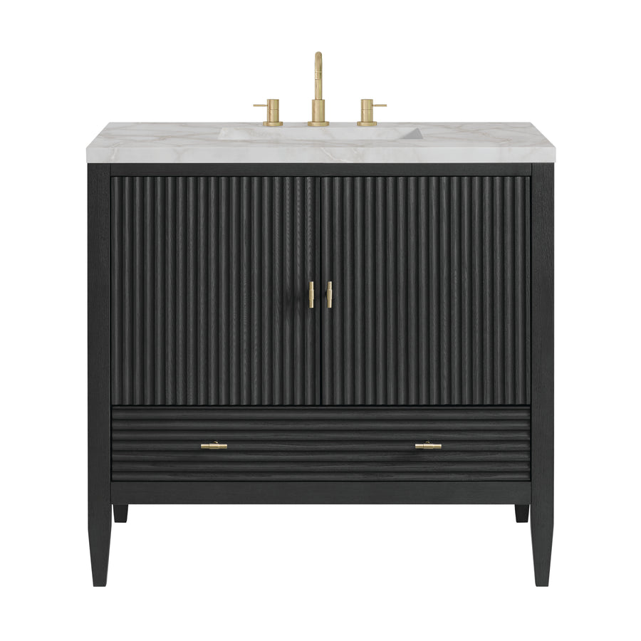 Black bathroom vanity with fluted double doors, a lower drawer, gold handles, and a white marble countertop featuring a gold faucet and handles.