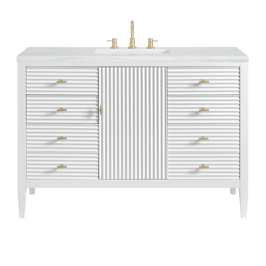 White bathroom vanity with a fluted center cabinet, eight side drawers, gold handles, and a gold faucet on a white countertop with an integrated sink.