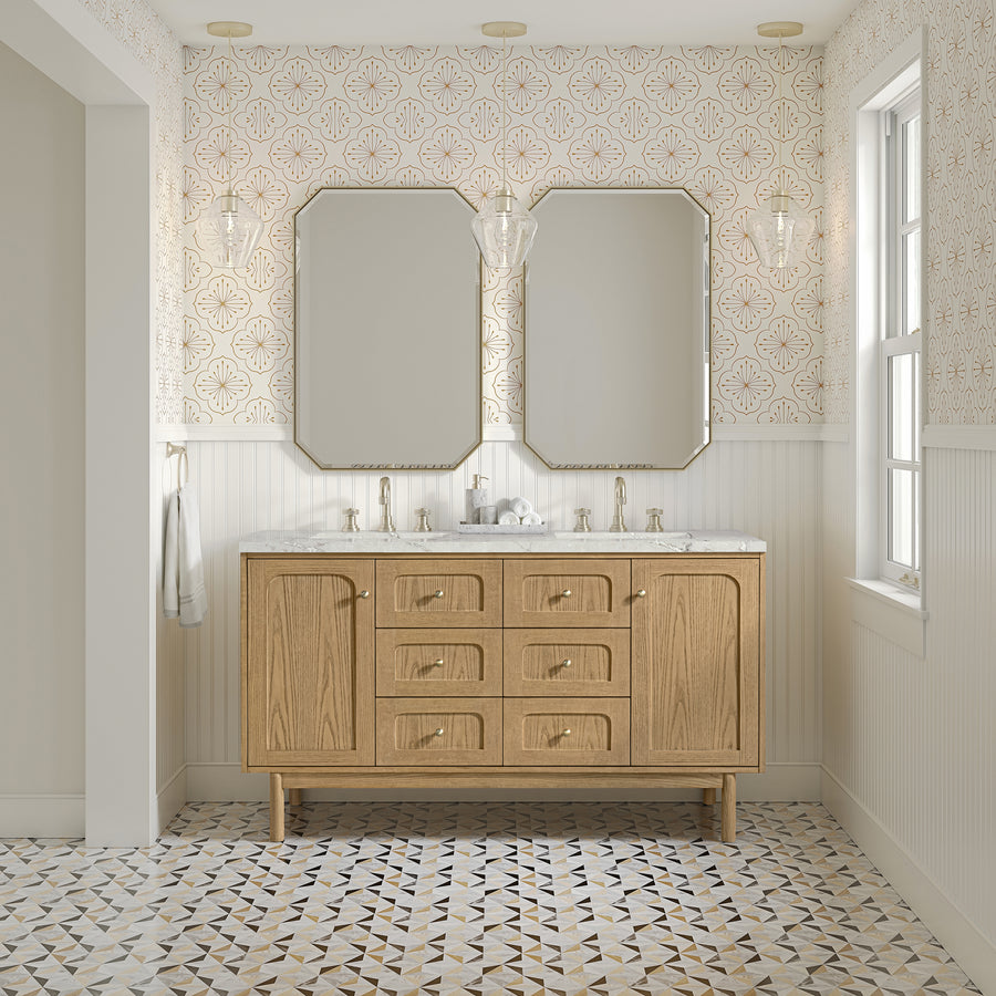 A bathroom with patterned tile flooring, beige wallpaper, a Laurent 60" Double Bowl Vanity in light oak with drawers and dual sinks, two octagonal mirrors, brass fixtures, pendant lights, and a right-side window letting in natural light.