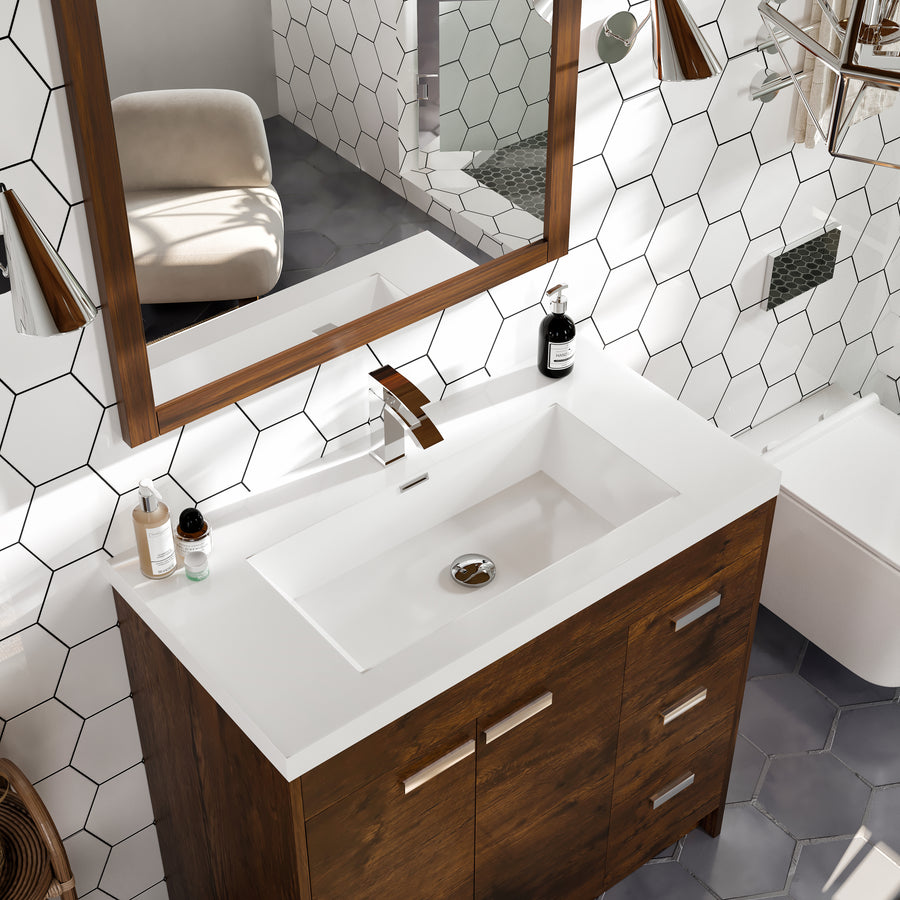 A modern bathroom with a white rectangular sink set in a wooden vanity, hexagonal wall tiles, a large mirror with a wooden frame, and toiletries placed on the countertop. A chair and toilet are visible in the background.
