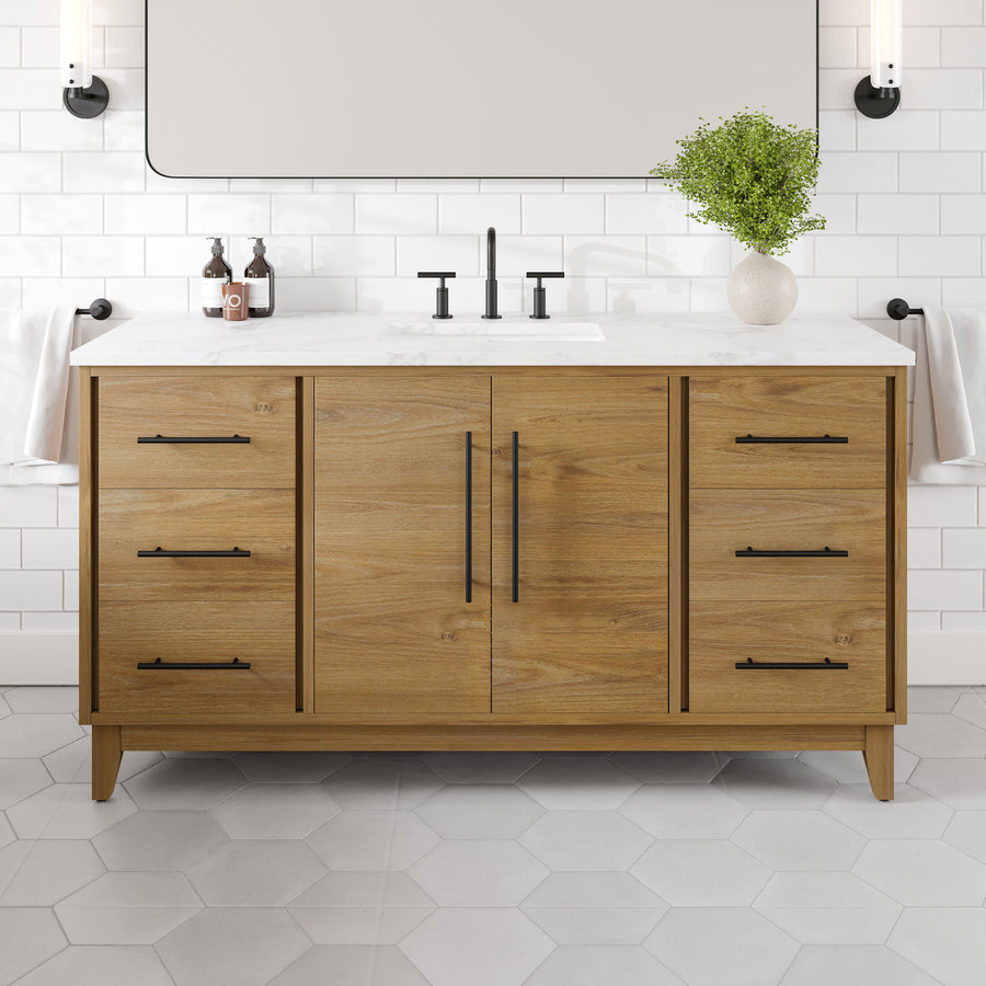Graham 60" Transitional Vanity: This modern bathroom centerpiece showcases an oak wooden cabinet with six spacious drawers and a sophisticated Arabescato engineered top. The countertop is styled with a faucet, soap dispensers, and a green plant for added freshness. Finished with a classic white subway tile backsplash and hexagonal floor tiles, this luxurious vanity seamlessly blends transitional style and functional design.