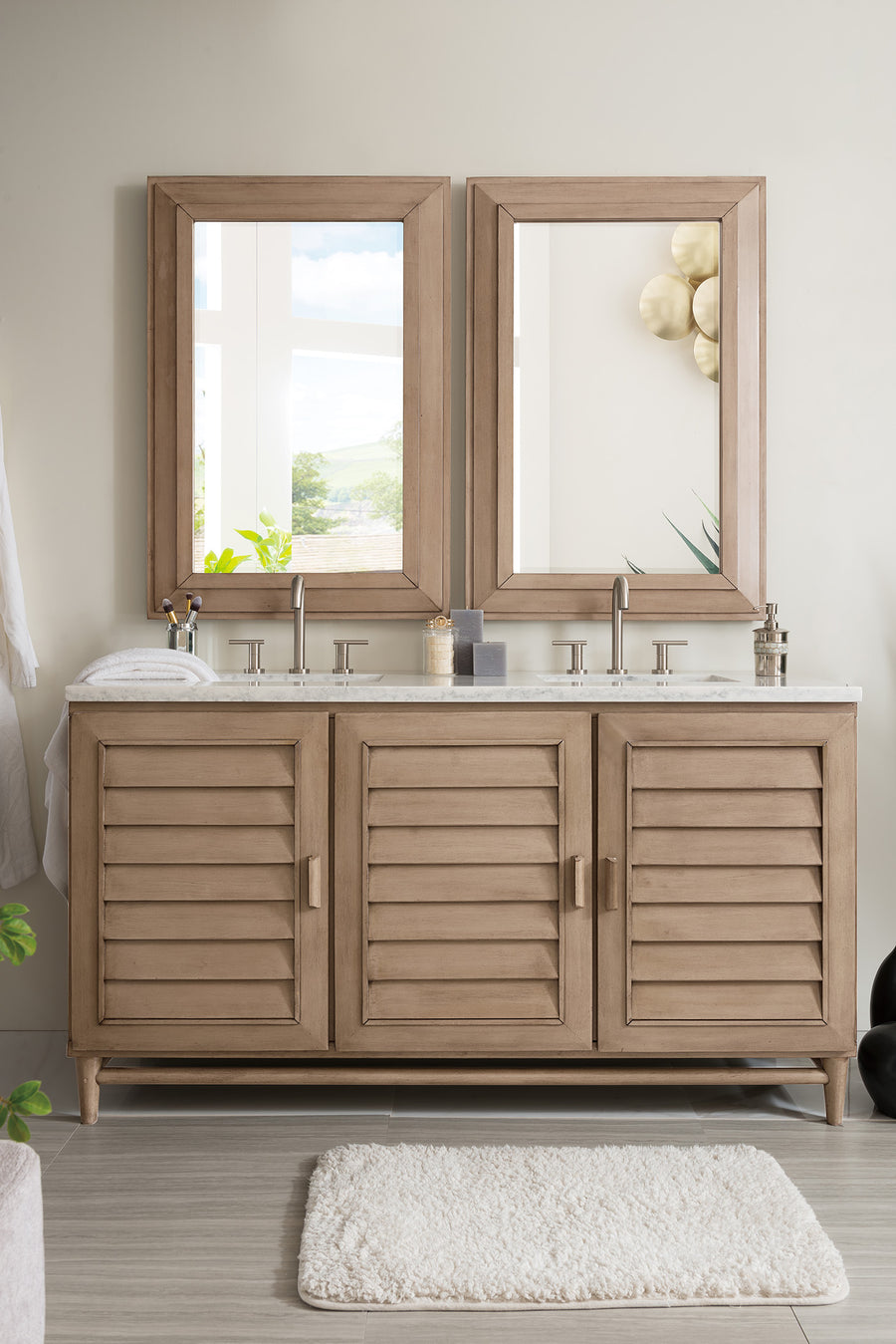 The Portland 60" Double Bowl Vanity features a modern light wood finish, double sinks, two mirrors, soap dispensers, a towel, and decor on the counter, with a white rug placed in front.