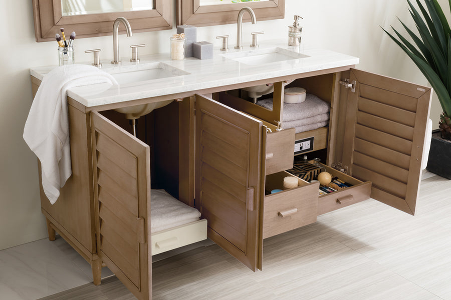Double bathroom vanity with two sinks and mirrors, light wood cabinets and drawers open to reveal neatly organized towels, toiletries, and accessories on shelves and in organizers, on a light tile floor.
