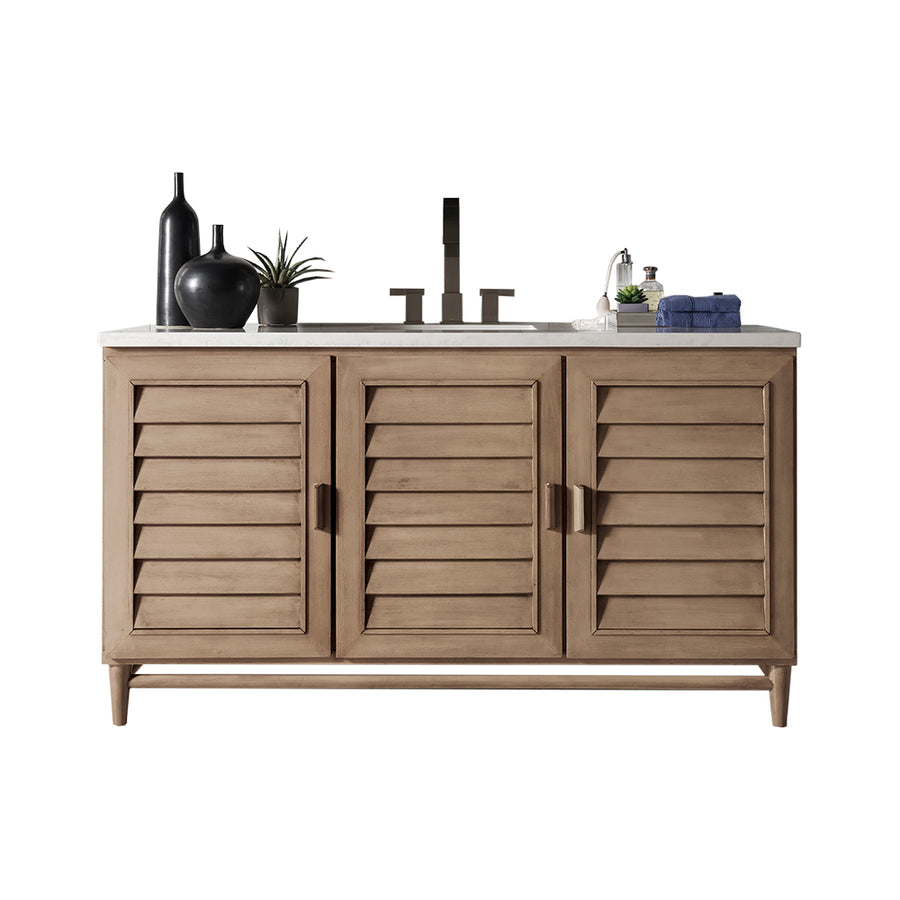 Brown wooden vanity with three louvered cabinet doors, a white countertop, a faucet, potted plants, decorative vases, a soap dispenser, and neatly folded hand towels on top.