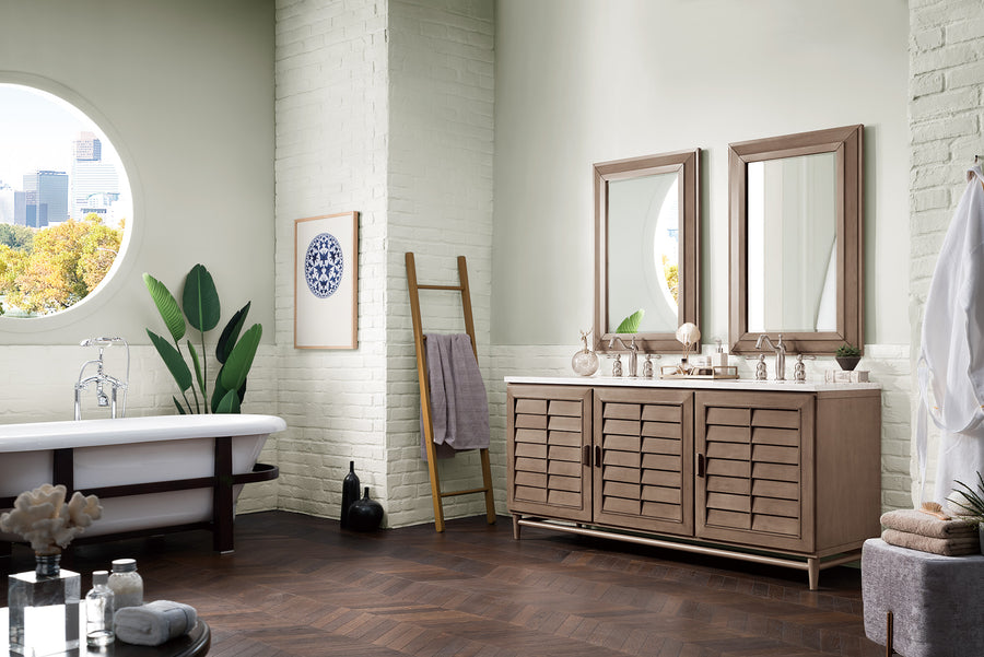 A modern bathroom with a freestanding tub, double-sink vanity with mirrors, a wooden ladder holding towels, potted plants, and a round window showing a cityscape outside. The decor features light walls and dark wood flooring.