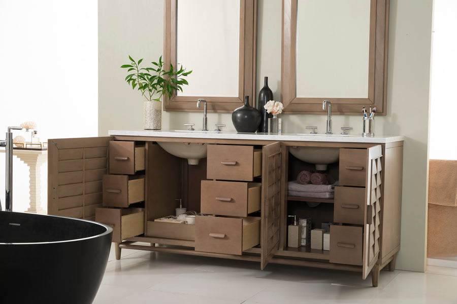 A modern bathroom vanity with two sinks, wooden cabinets and drawers open, displaying neatly organized towels, toiletries, and decor items. A plant and vases sit on the countertop beneath two mirrors.