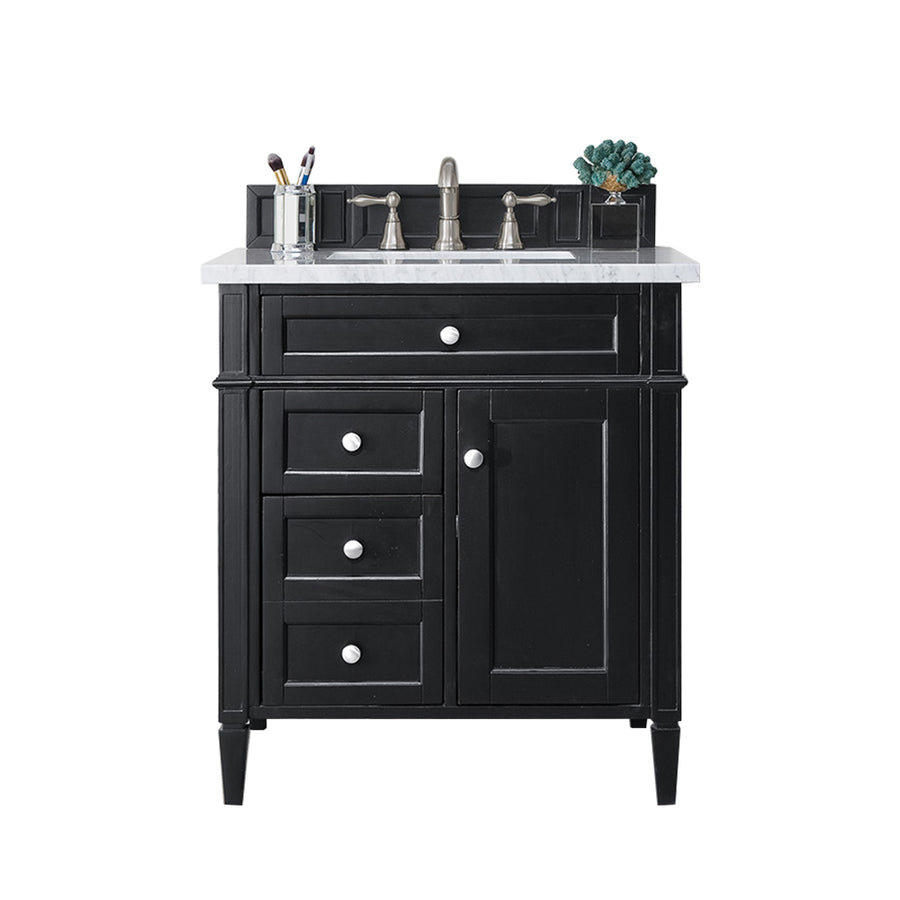 A black bathroom vanity with a white countertop, single sink, silver faucet, and storage drawers. Toothbrushes and a plant are placed on the back edge of the countertop.