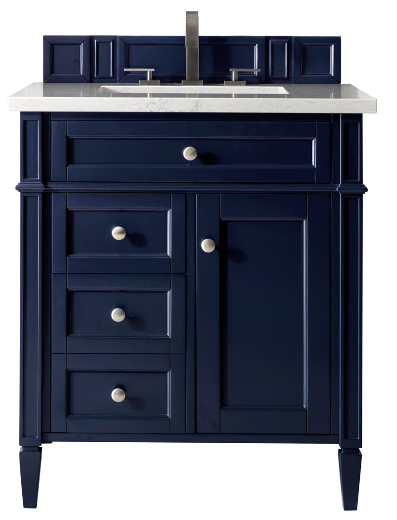 A navy blue bathroom vanity with silver knobs, four drawers on the left, a cabinet door on the right, and a white countertop with a modern faucet and sink.