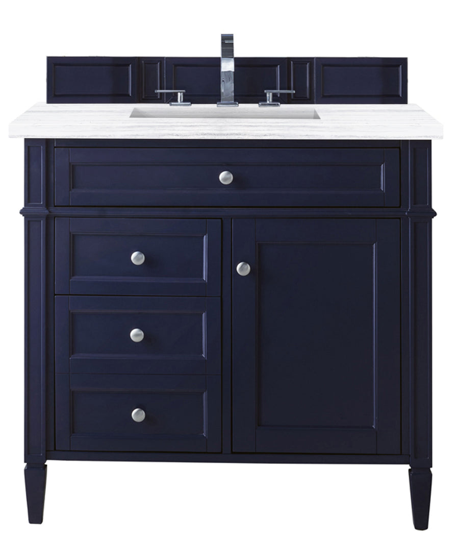 A navy blue bathroom vanity with a white countertop, silver handles, three drawers on the left, and a cabinet door on the right, featuring a silver faucet and backsplash.