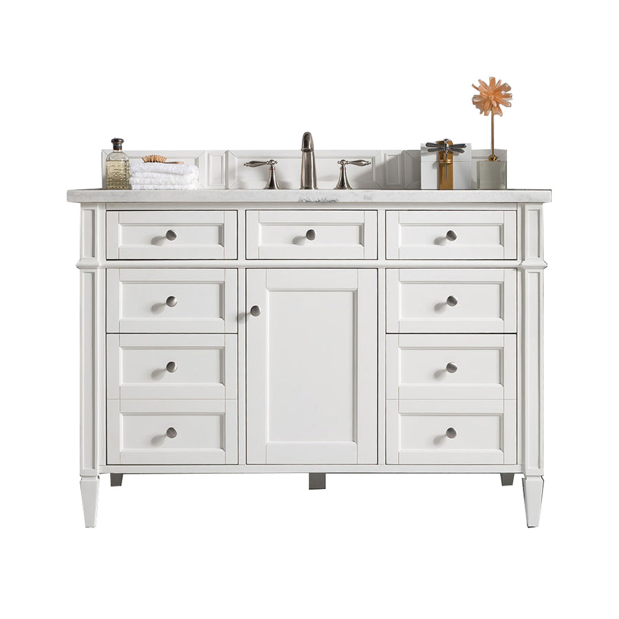 White bathroom vanity with a marble top, silver faucet, nine drawers, a center cabinet, and toiletries, towel, soap dispenser, and decorative items arranged on the countertop.