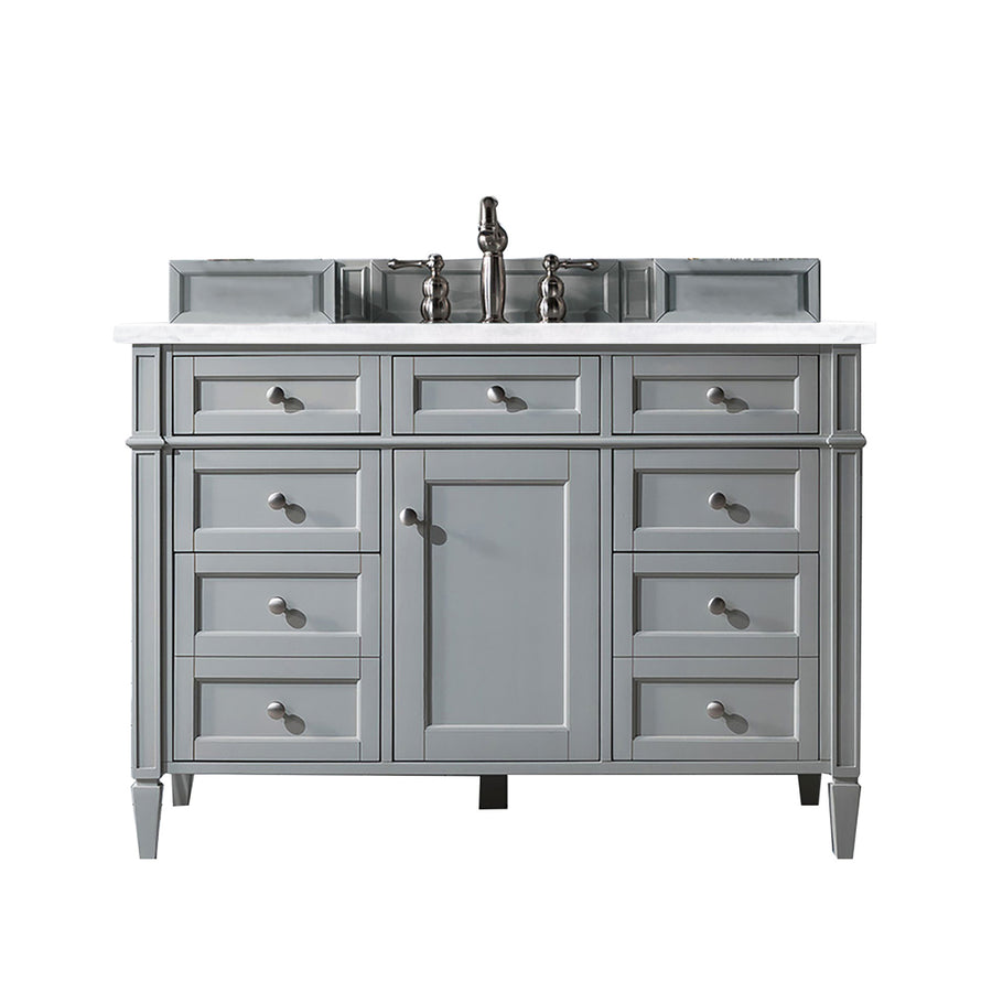 A gray bathroom vanity with a white countertop, central cabinet doors, six side drawers, and a mounted faucet. The design is classic with round drawer knobs and raised panel detailing.