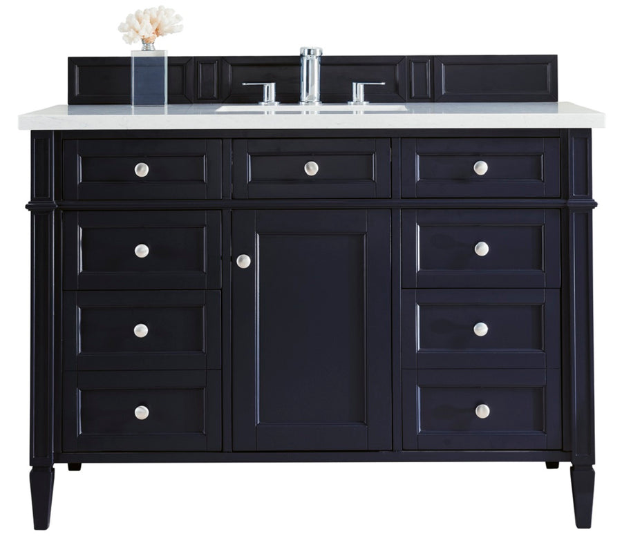A black bathroom vanity with a white countertop, silver faucet, and cabinet knobs. It has a central sink, six drawers, one cabinet door, and a small decorative item on the left side of the counter.