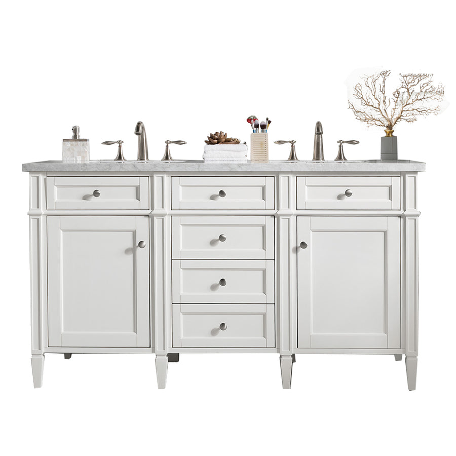 White double-sink bathroom vanity with silver hardware, marble countertop, and four central drawers. Countertop items include soap dispenser, cup with toothbrushes, pinecone, and decorative coral branch.