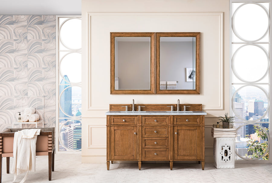 A modern bathroom showcases the Brittany 60" Double Bowl Vanity with a wood finish, two large framed mirrors, circular city-view windows, and chic decor like a plant, rolled towels, and a small white side table.
